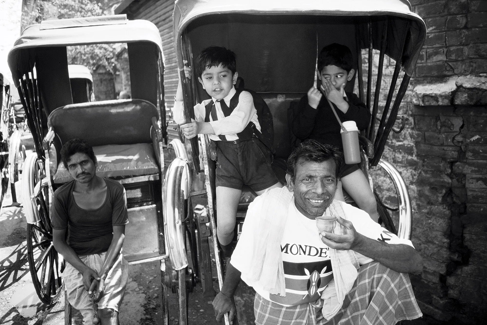 Bangladeshian family outside sitting in rickshaws with one man wearing a Mondetta Everywear Kenya t-shirt.