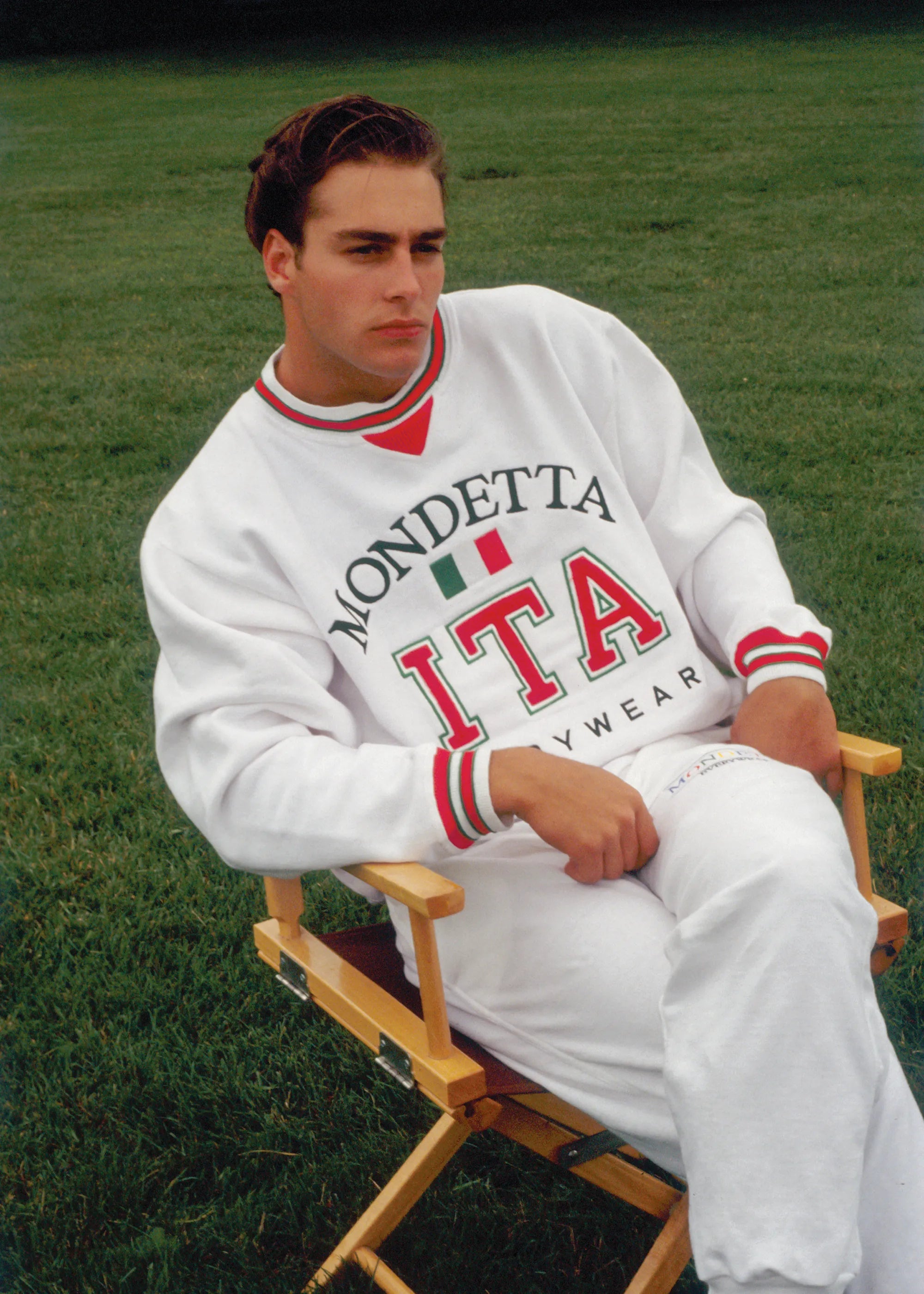 Man outside in a directors chair on a lawn wearing white Mondetta Everwear Italy sweatshirt.