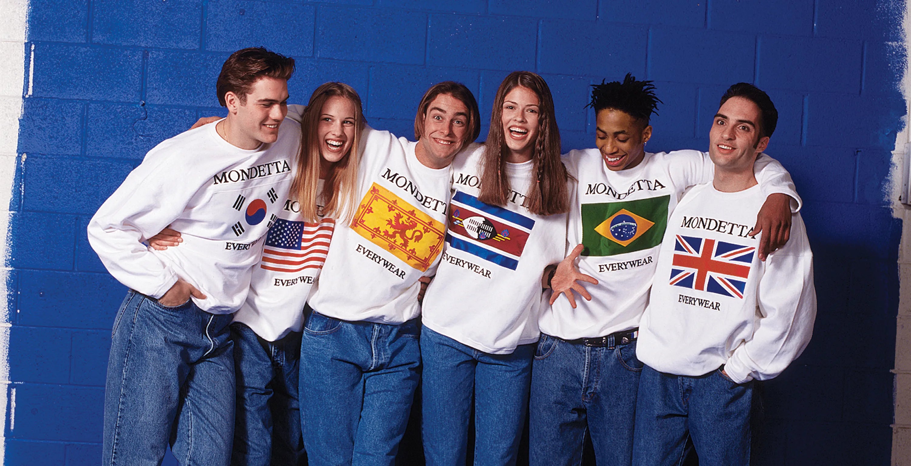 Group of laughing people wearing classic Mondetta Everwear country flag white sweatshirts.